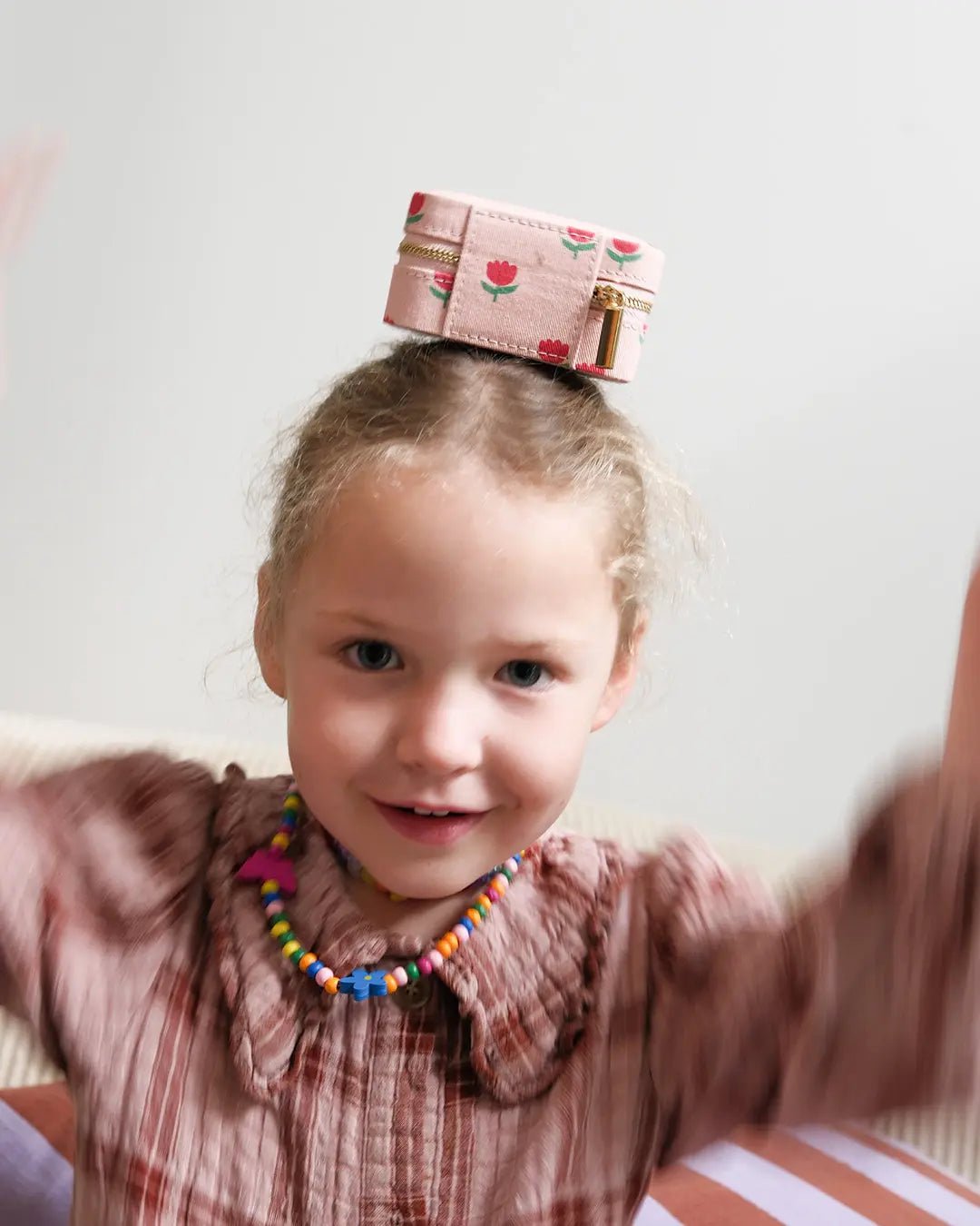 Enfant souriant avec une boite à bijou à motif fleurs sur la tête