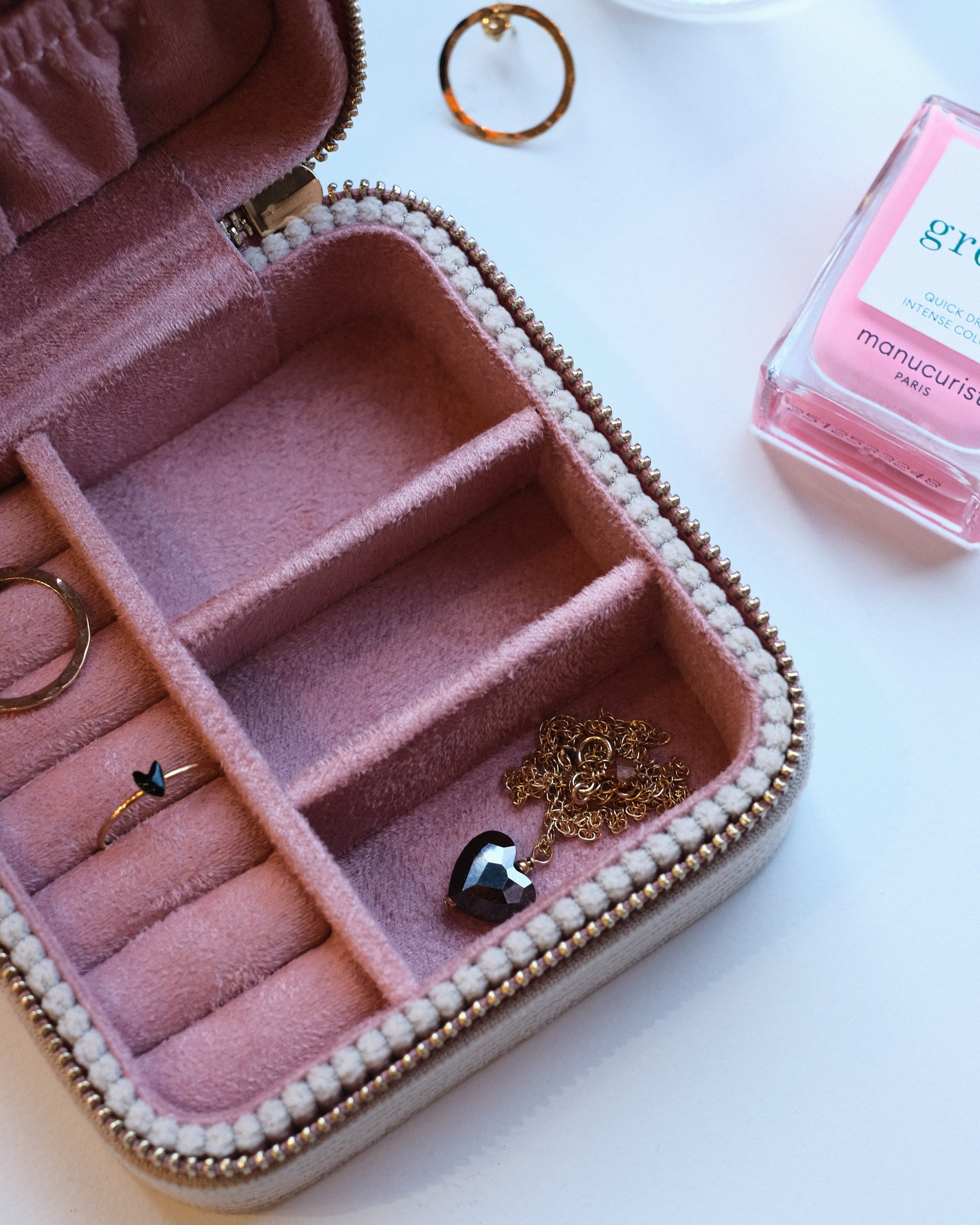 boite à bijou ouverte rose avec bijoux dedans : collier, bague